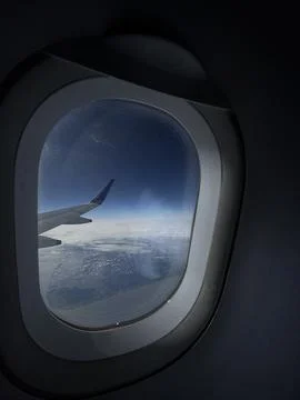 Airplane window mood light with wing above clouds capturing quiet remote wo.. Stock Photos