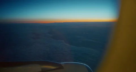 Airplane Window View Above Blue Clouds with Yellow Orange Horizon Stock Footage 343594282