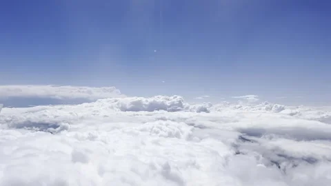 Airplane window view above bright white cloud layers, with blue sky, high Stock Footage 342999363