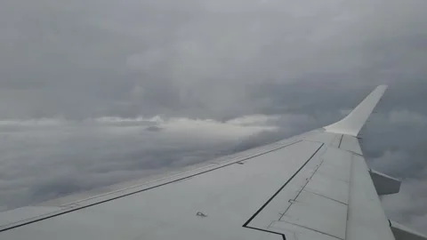 Airplane window view above dark storm clouds, with the wing visible. Dramatic 스톡 동영상 342073578