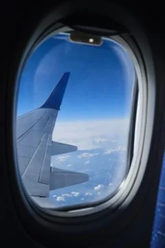 Airplane window view on the clouds and blue sky horizon. Plane wing vertical Foto stock