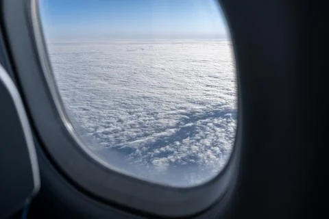Airplane window view with clouds below from passenger seat travel perspective Fotos Stock