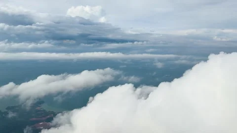 Airplane Window View Descending Through Clouds Toward Coastline Stock Footage 323777561