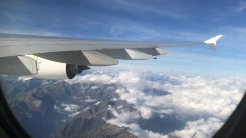 Airplane window view down to Alps mountains / landscape with cloud, Swiss. 4K Stock Footage 197699280