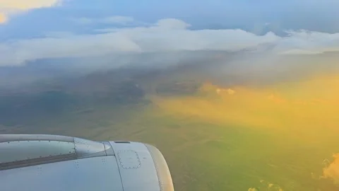 Airplane window view of dramatic clouds and golden sunlight over farmland Vidéo 334737099