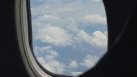 Airplane Window View of Fluffy Clouds and Blue Sky During Long Haul Flight Stock Footage 342898311