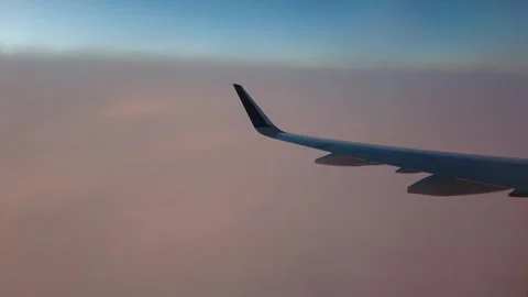 Airplane window view flying at same height as cloud level sunset golden hour Stockbeeldmateriaal 260349357