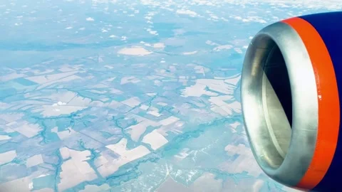Airplane Window View Jet Engine Above Clouds and Farmland Stock Footage 329623024