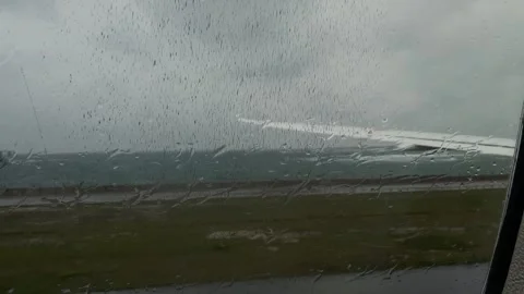 Airplane window view of plane wing during takeoff rainy rain drops over glass Stockbeeldmateriaal 344554570