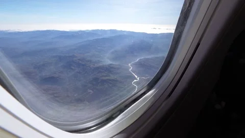 Airplane window view of a shining river and mountains Stock Footage 339353875