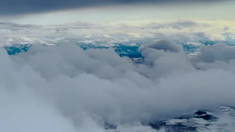 Airplane window view of snow-covered Bavarian Alps with dramatic winter clouds Stock Footage 333010632