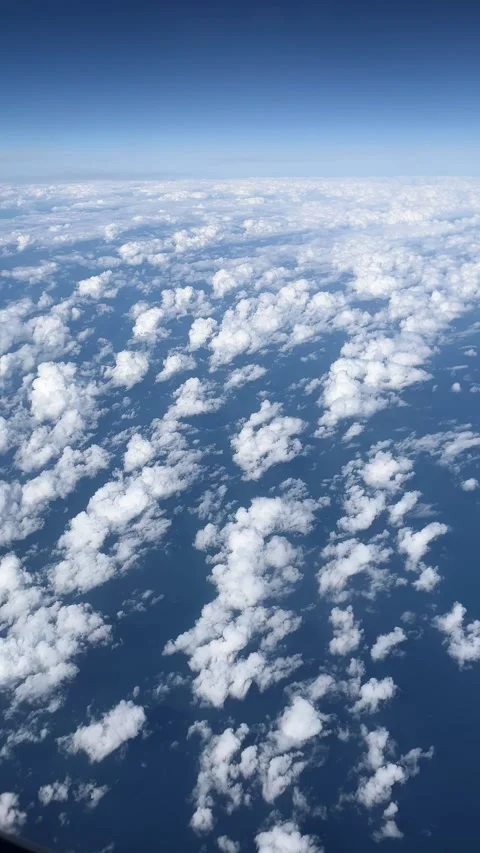 Airplane window view of textured clouds over the blue atmosphere while cruising Stock Footage 344412158
