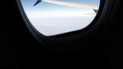 Airplane Window View with Wing and Ground in Focus, Tilt Up Shot Stock Footage 146560655