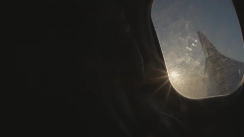 Airplane window view of wing and sun flare with passenger silhouette Video stock 341779354