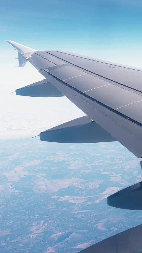 Airplane wing above a bright patchwork landscape, filmed from a passenger Stock-Footage 336214651