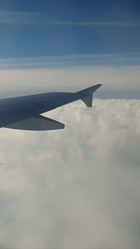 Airplane Wing Above Clouds in Clear Sky, Close-up of an airplane wing flying Stock Footage 310313547