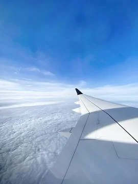Airplane wing above clouds during flight. Stock Photos