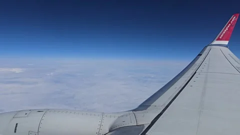 Airplane wing above clouds with Norwegian logo during cruise flight Stock Footage 345151945