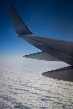 Airplane wing above the clouds Stock Photos