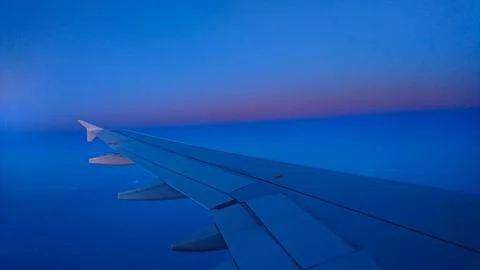 Airplane wing above clouds at sunset with vibrant colours Stock Photos