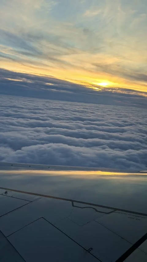 Airplane Wing Above Dense Clouds at Sunset Viewed From Passenger Window Seat Stock Footage 335262710