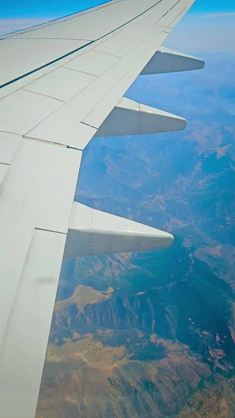 Airplane wing above dramatic mountain ridges during scenic flight, view through Stock Footage 346285763
