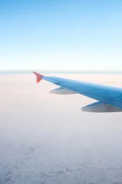 Airplane wing above fluffy clouds on a clear day during daylight hours Stock Photos