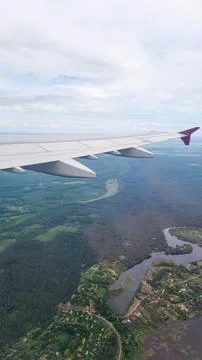 Airplane wing above green forest landscape with winding river and countryside vi Fotos Stock