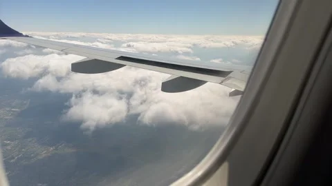 Airplane wing above soft cloudscape with distant view of land Stock Footage 310677524