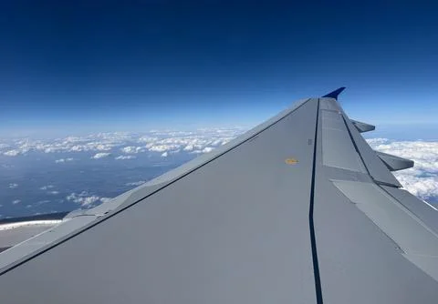 Airplane wing and cloud layer above earth horizon. Aerial travel, atmospheric Stock Photos