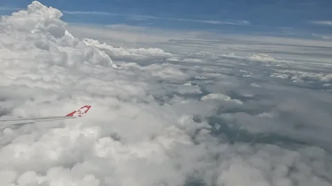 Airplane Wing and Cloudscape Seen from Passenger Window on Daytime Flight Over Stock Footage 343849882