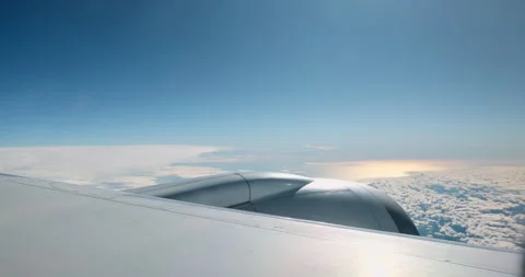 Airplane wing and engine flying above white fluffy clouds on a sunny day Stock Footage 336952875