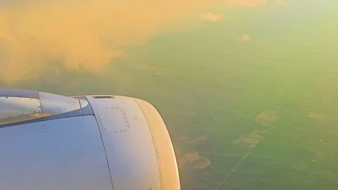 Airplane wing and engine over patchwork fields as sunlight breaks through Video stock 334600780