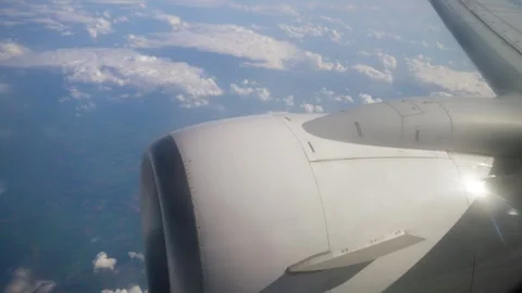 Airplane Wing and Engine View Above Fluffy Clouds During Daytime Flight Over Stock Footage 303572515