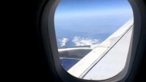 Airplane wing and engine view from window, showcasing clouds and blue sky Stock Footage 344516181