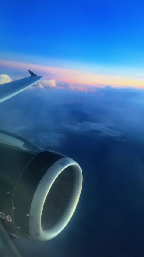 Airplane Wing and Jet Engine Flying Above Clouds at Sunset with Pink Sky. Stock Footage 338360347