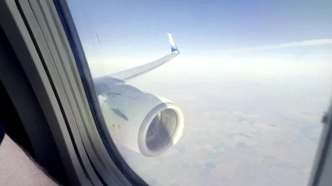 Airplane wing and jet engine seen from a passenger window while flying over Video stock 338994470