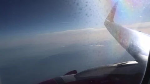 Airplane wing catches bright sunlight through dusty window with soft clouds and  Stock Footage 310856610