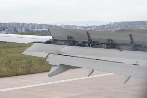 Airplane wing with deployed flaps and spoilers during landing Stock Photos