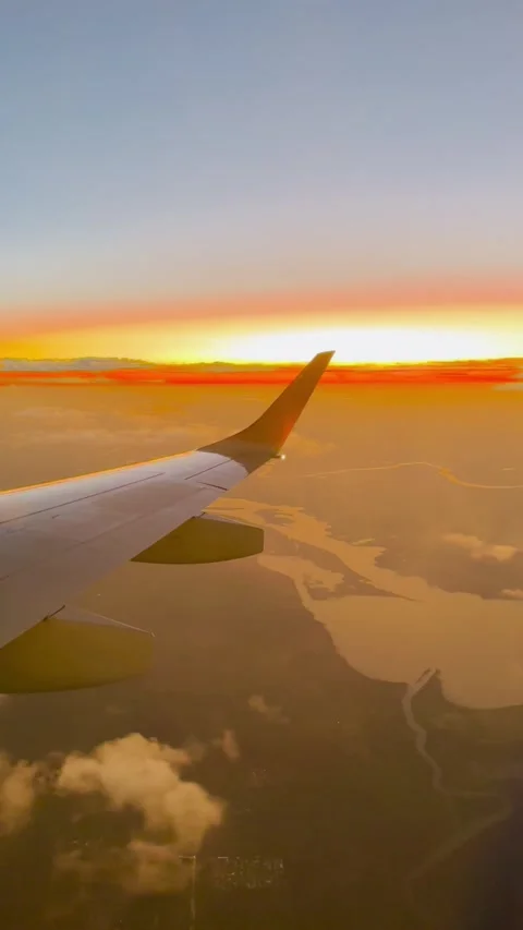 Airplane wing during a vibrant sunset over a landscape with water bodies. Stock Footage 276876924