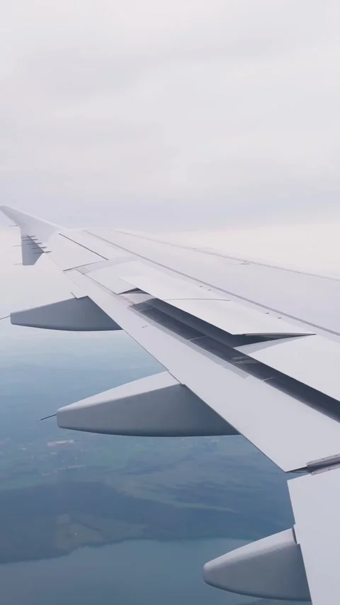Airplane wing with extended flaps during a turbulent descent, capturing Stock Footage 333655695