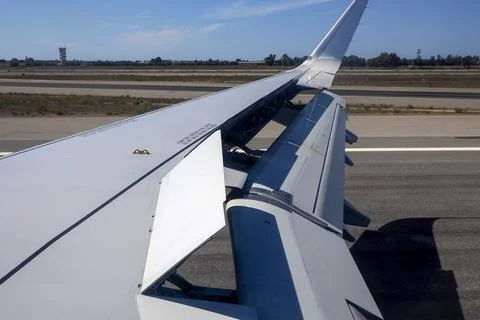 Airplane Wing With Extended Flaps During landing Roll Over Runway At Airport Stock Photos