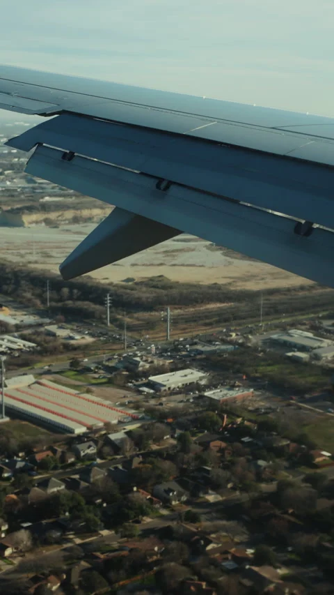 Airplane wing with flaps down on approach over suburbs Stock-Footage 347966865