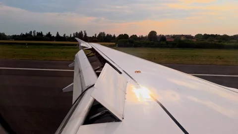 Airplane wing with flaps extended during takeoff at sunset Stock Footage 342201529