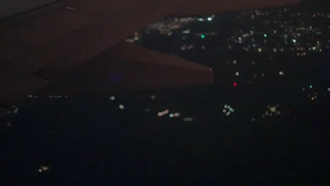 Airplane wing flaps over blurry city lights at night Stock-Footage 347984187