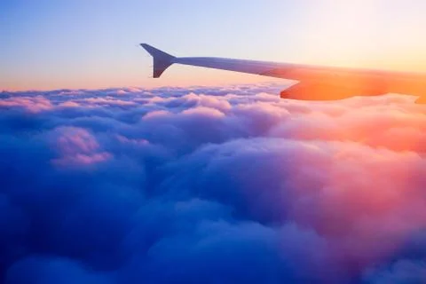 Airplane Wing in Flight from window, sunset sky Stock Photos