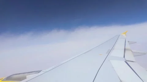 Airplane wing flying above the clouds in blue sky Stockbeeldmateriaal 345806575