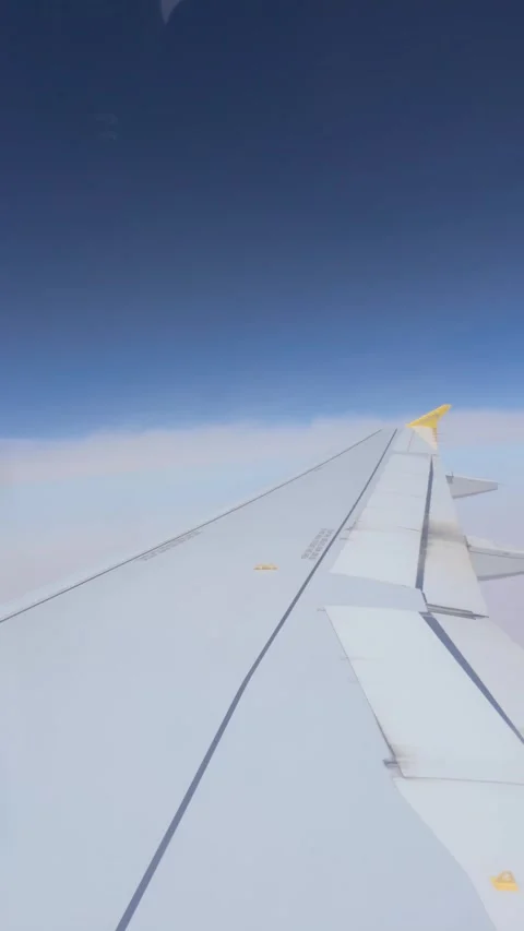 Airplane wing flying above the clouds in slow motion Stock Footage 345808918