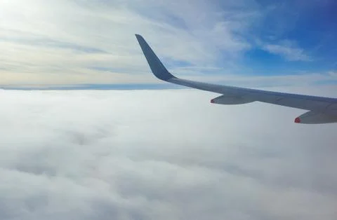 Airplane wing flying above clouds in blue sky Stock-Fotos
