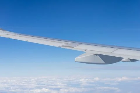 Airplane wing flying above clouds in blue sky Stock Photos
